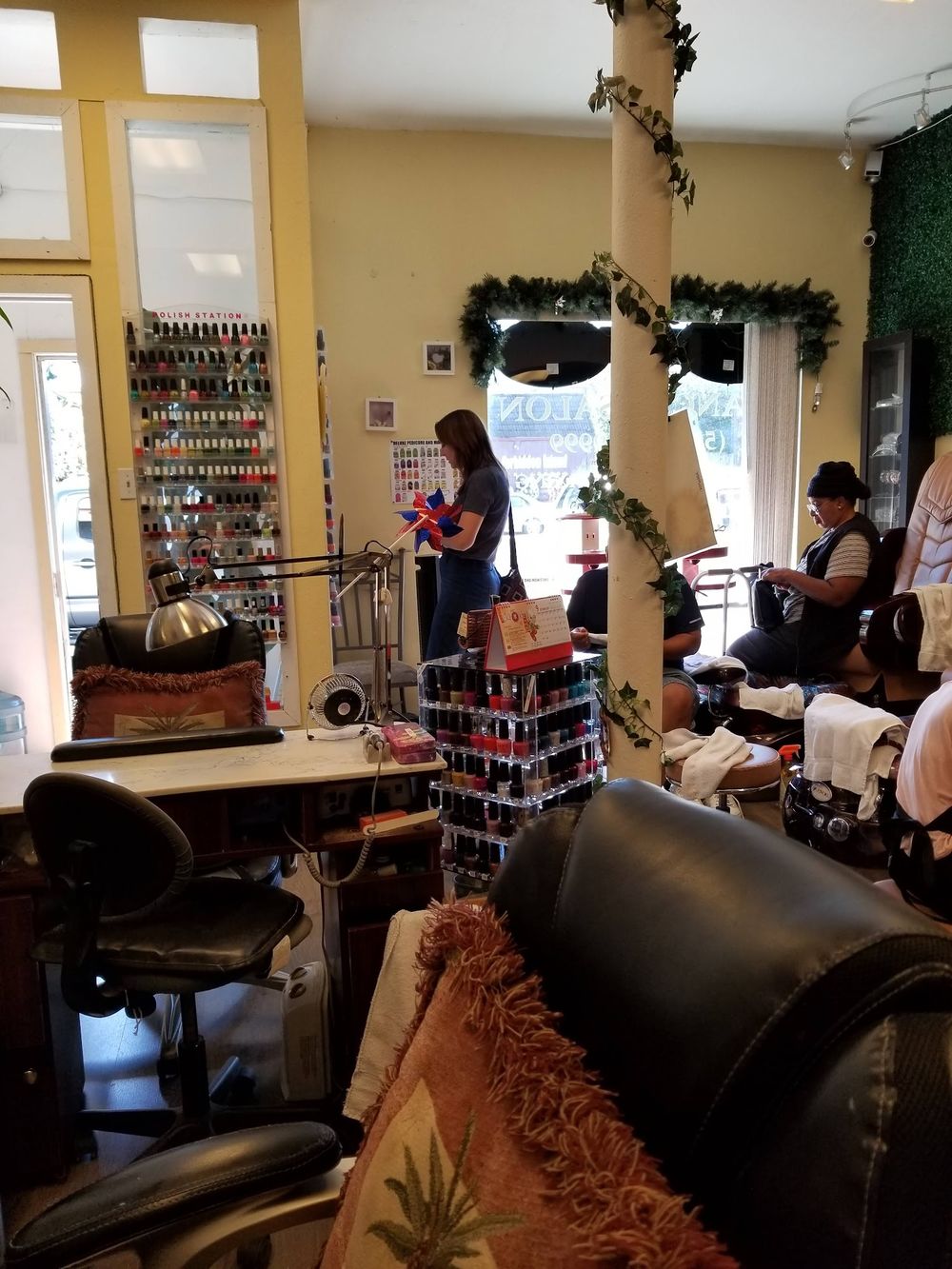 Inside Nancy’s Salon: manicure tables, a polish wall and pedicure chairs under tall windows